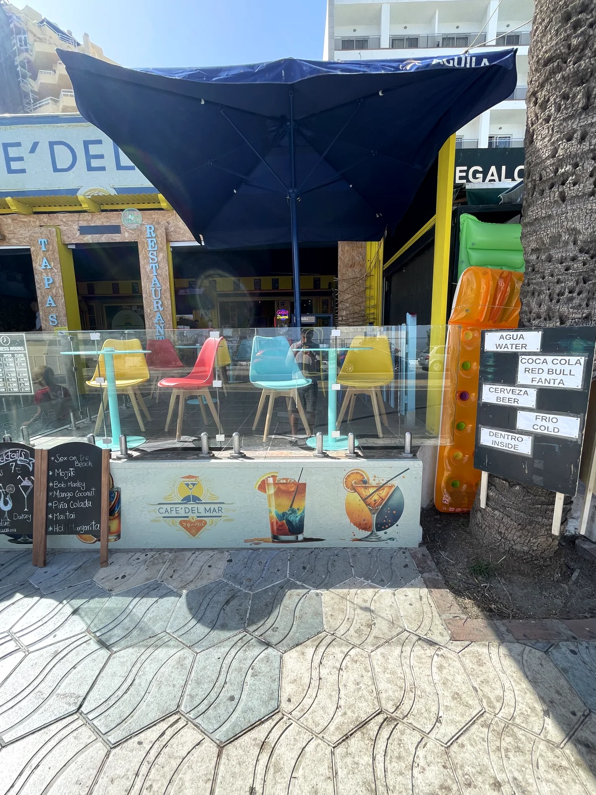 Terraza exterior de Café Del Mar con mesas de colores